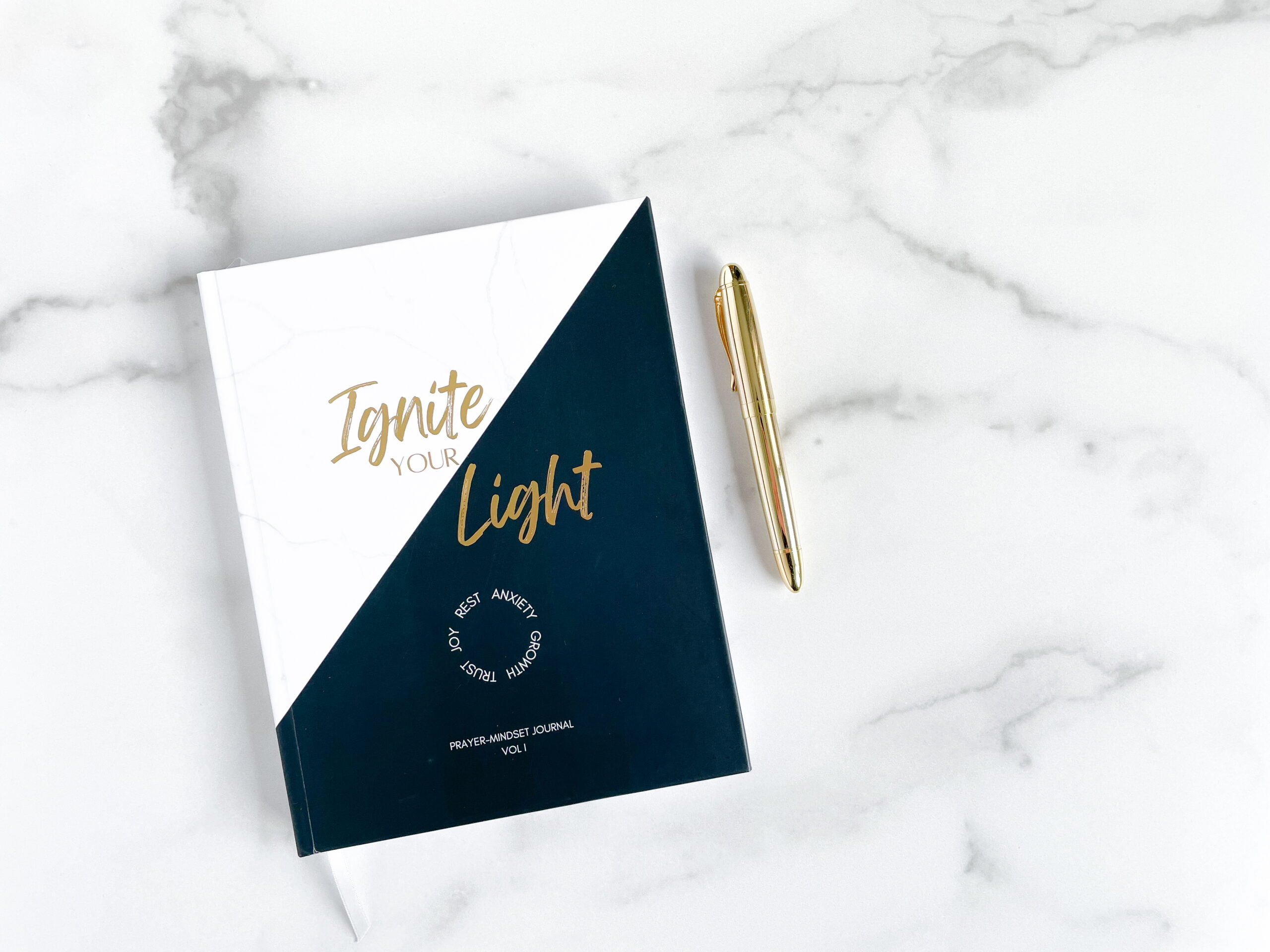 photo of a journal: Ignite Your Light with a gold pen on a white/gray marble background